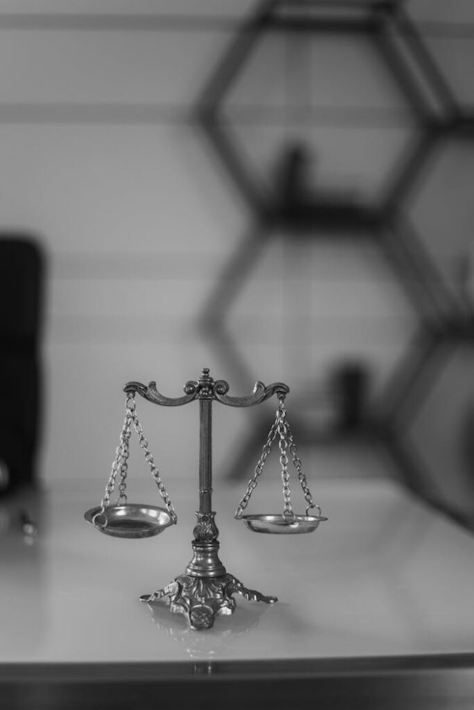 A black and white photo of a vintage balance scale in an office environment, emphasizing symmetry and justice.